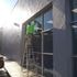 Worker cleaning high windows on a sunny day using a ladder